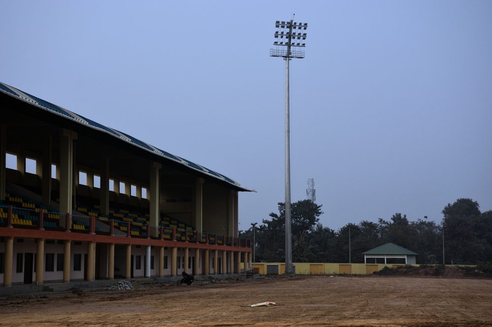 Stadium mast carrying floodlights beside a pavilion
