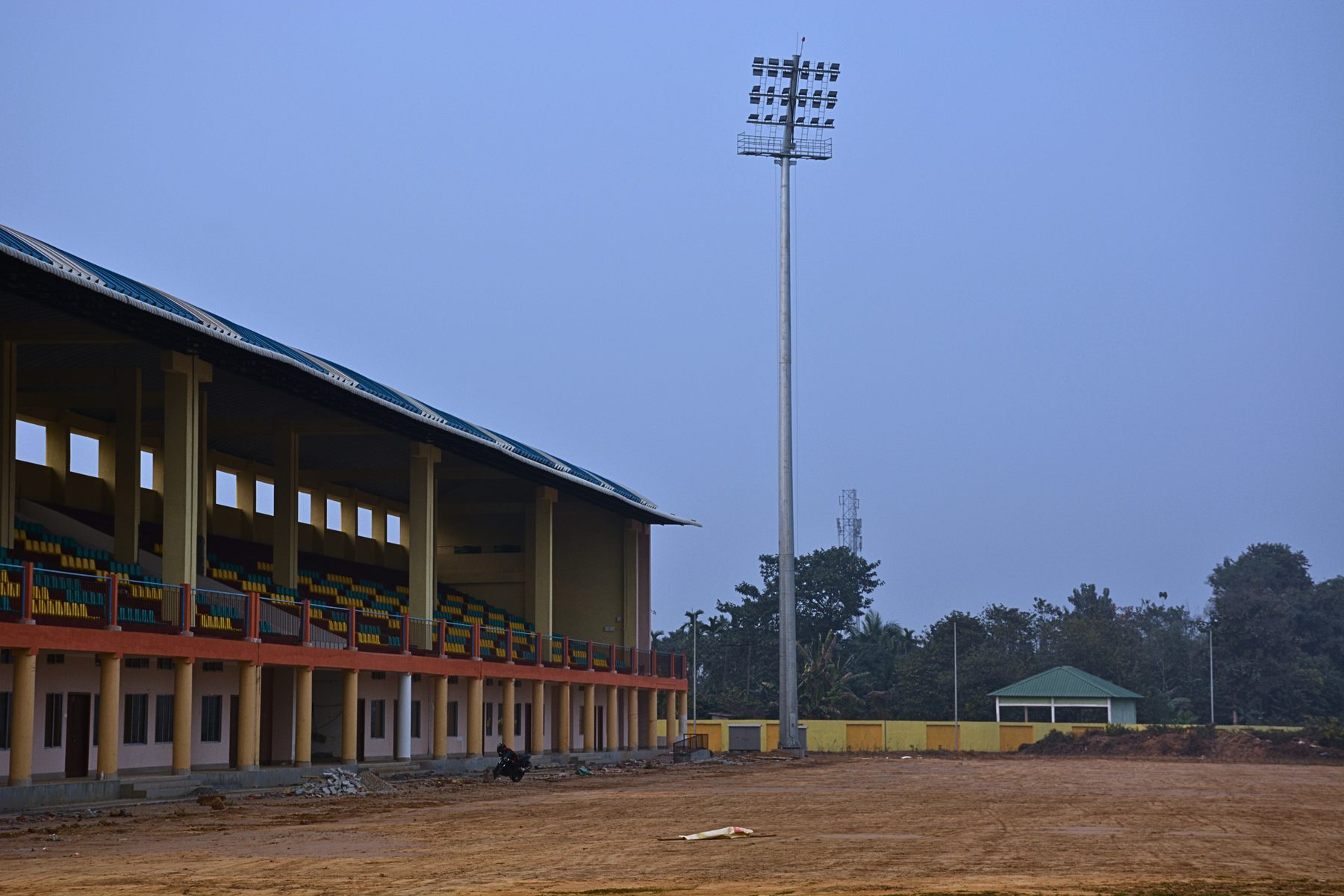 Floodlit 35 metre mast standing beside the pavilion at Dudhnoi Stadium